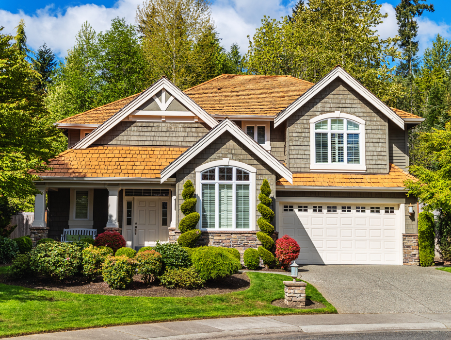 Shingle-style home framed by mature trees and landscaped gardens.